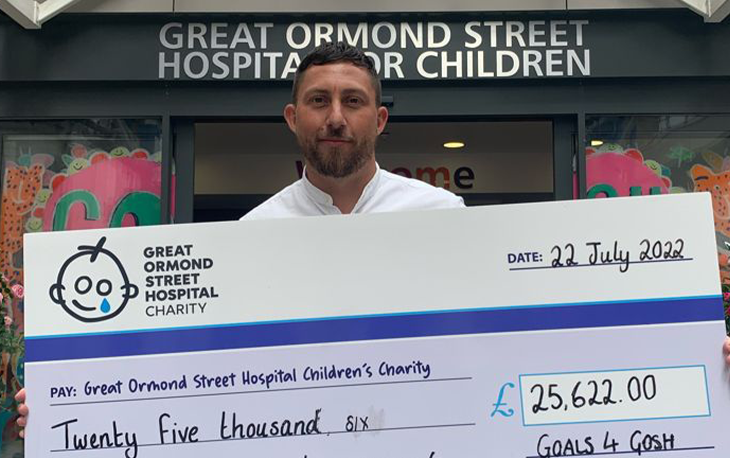 A man holds a giant cheque to Great Ormond Street Hospital Charity