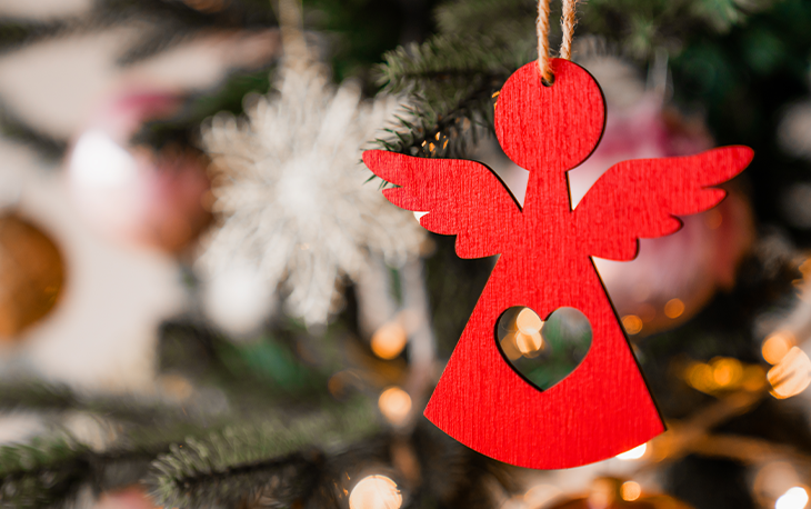 A Christmas Ornament in the shape of an Angel hanging on a tree