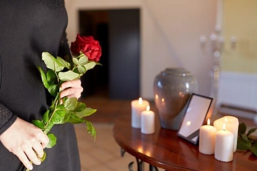 man with roses looking at table with urn and candles